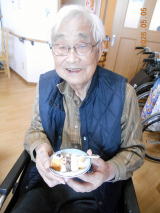 入居者が食事を楽しむ様子。白いお皿を持ち笑顔で過ごしている
